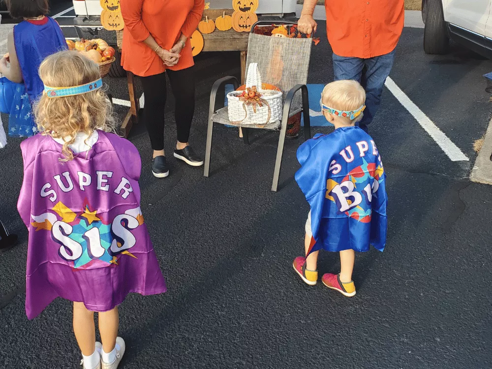 Two children wearing Super Sis and Super Bro capes during imaginative play