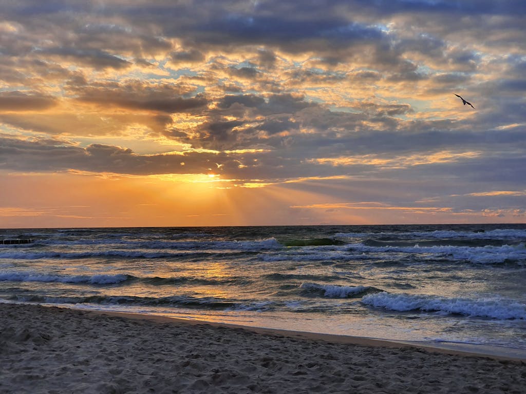 Gorgeous sunset over the ocean at Dziwnówek Beach, Poland with dramatic clouds and waves.