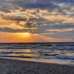 Gorgeous sunset over the ocean at Dziwnówek Beach, Poland with dramatic clouds and waves.