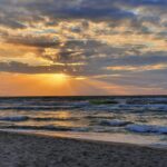 Gorgeous sunset over the ocean at Dziwnówek Beach, Poland with dramatic clouds and waves.