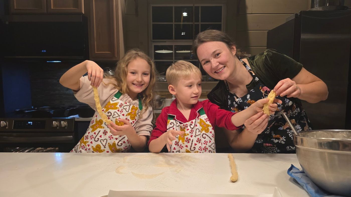 Children baking Christmas cookies with their mom as part of a cozy family Christmas tradition.
